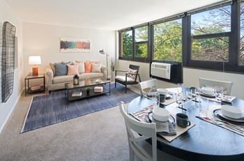 Living room layout with couch, dining set, and large windows at Eden Commons, Chicago